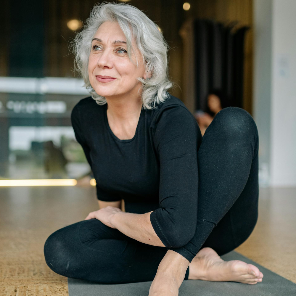 zdjęcie przedstawiajace dojrzałą kobietę ćwiczącą na macie spoglądającą w lewo